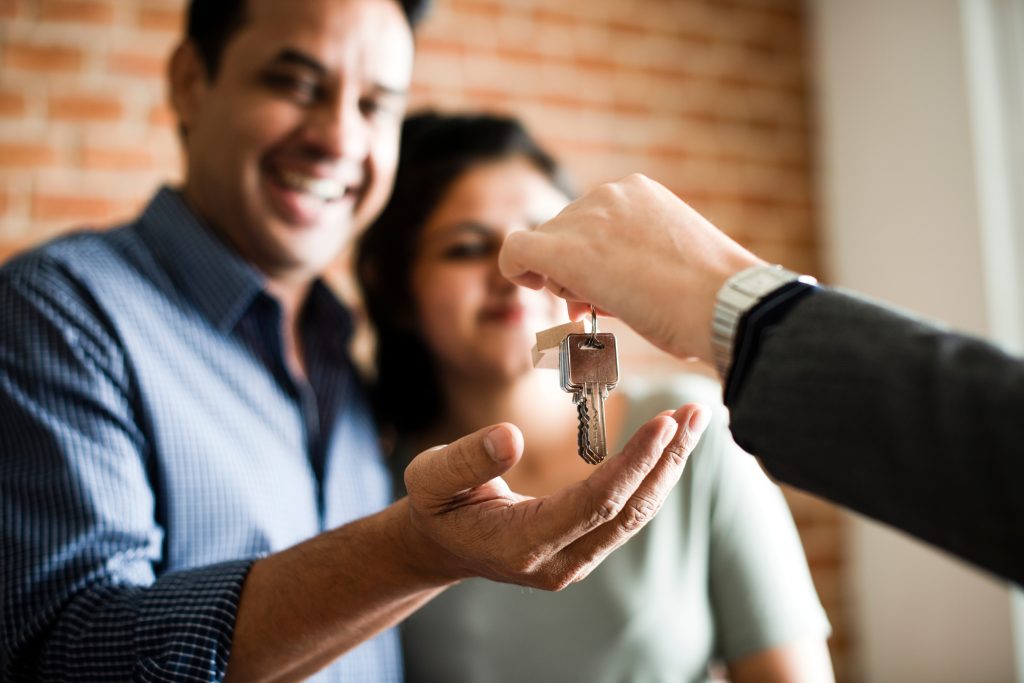 Hand of an agent is holding keys to give to new owners who are a Sri Lankan couple.