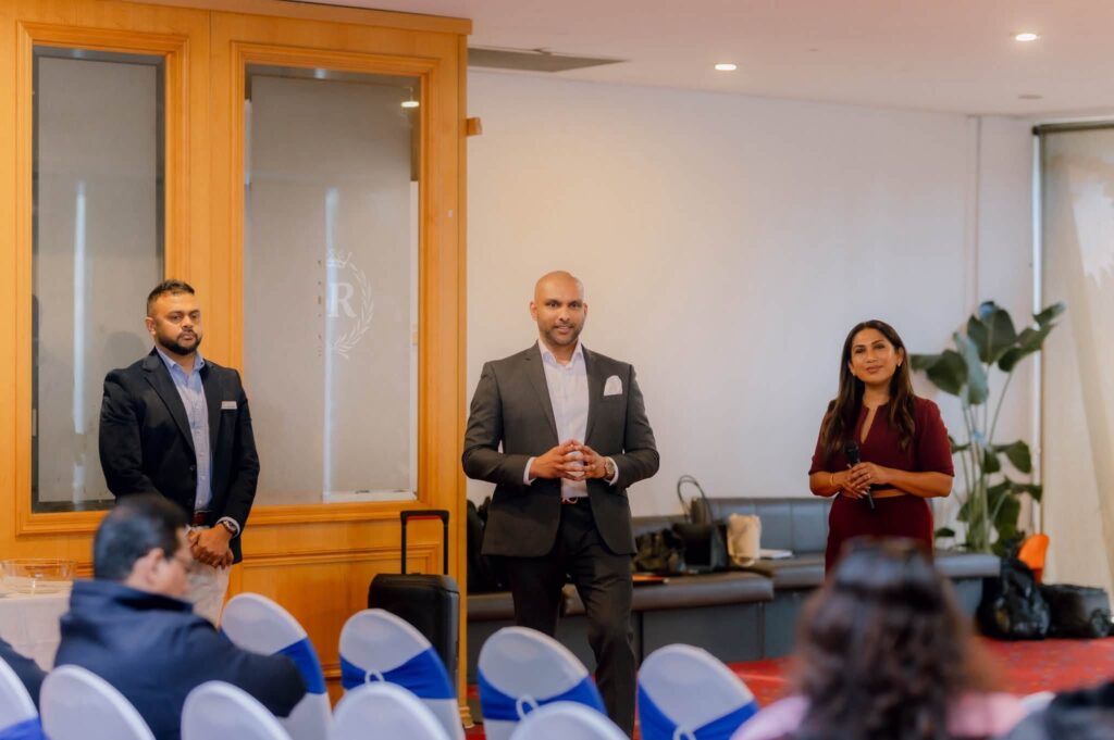 2 male and 1 female standing in front of an audience