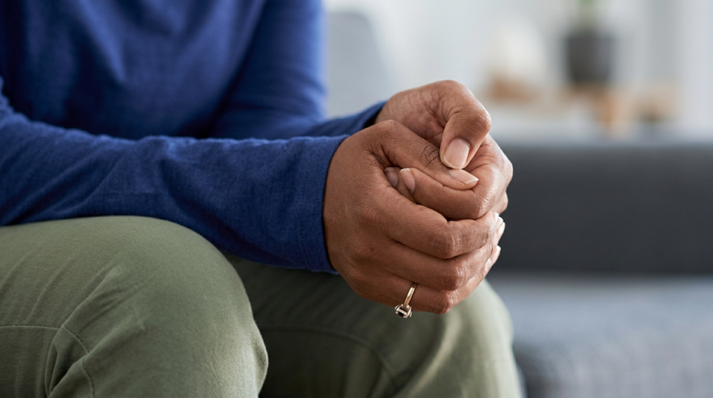 Worried woman sitting on a sofa and holding her hands.